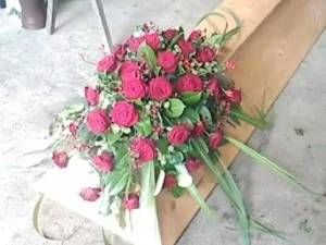 Sargschmuck aus roten Rosen