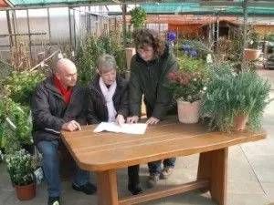 Drei Teammitglieder beugen sich über Plan auf einem Tisch