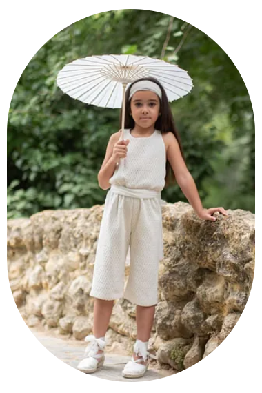 Una niña con un traje blanco sostiene un paraguas.