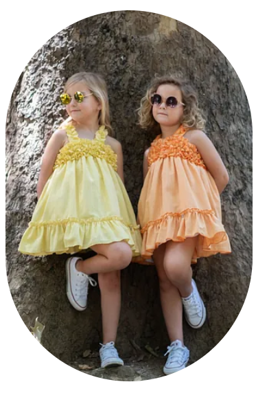 Dos niñas con vestidos y gafas de sol están sentadas una al lado de la otra.