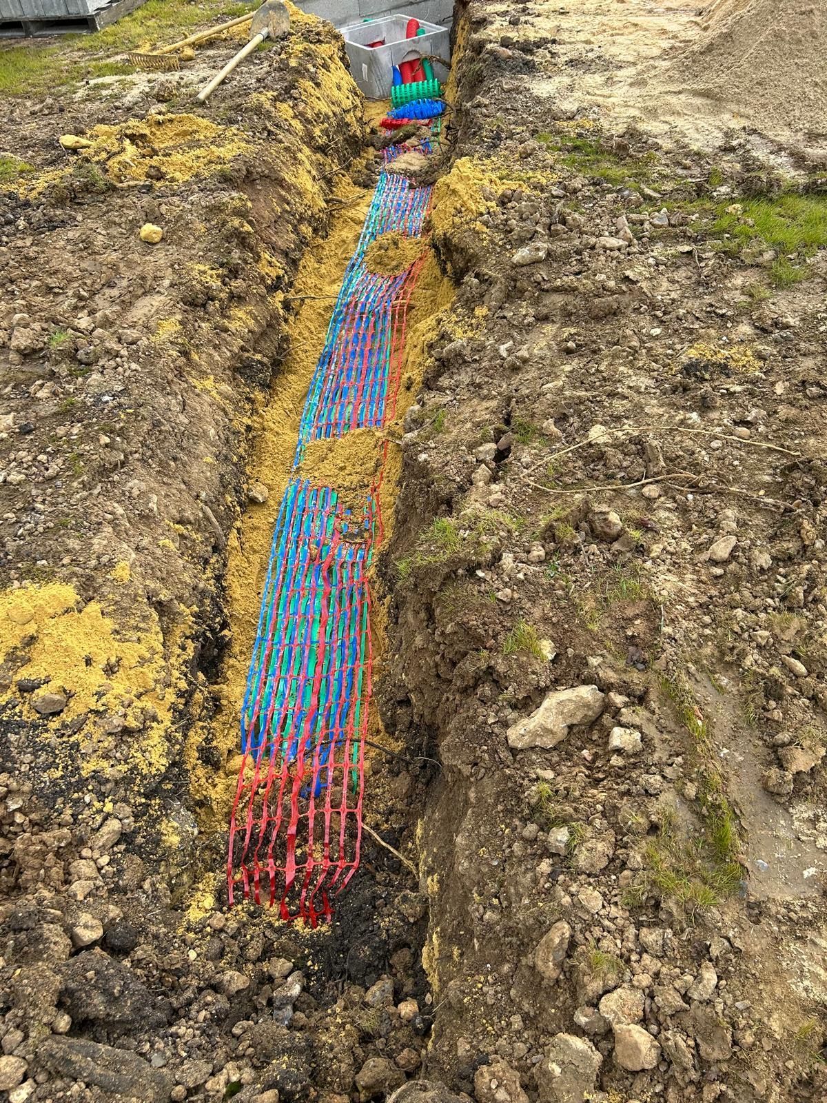 Câble utilitaire à code couleur dans une tranchée étroite de terre excavée