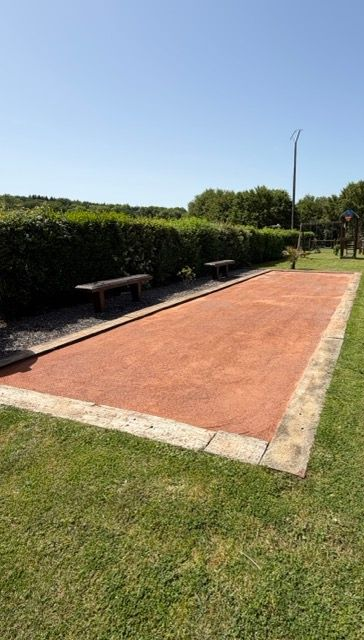 Terrain vague sablonneux jouxtant une maison, avec une fondation rectangulaire en béton au premier plan.