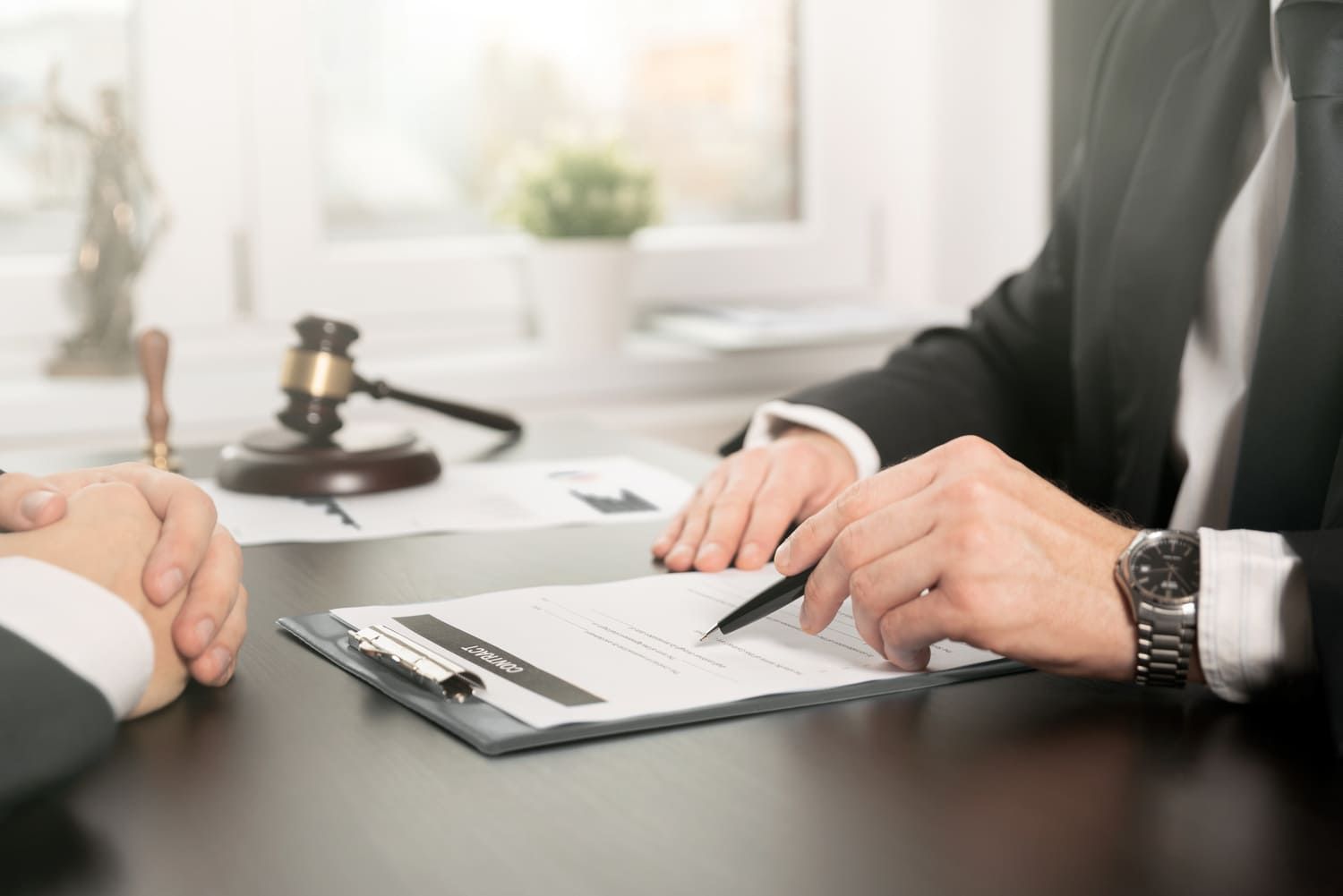 Un abogado está sentado en un escritorio con un cliente y firma un documento.