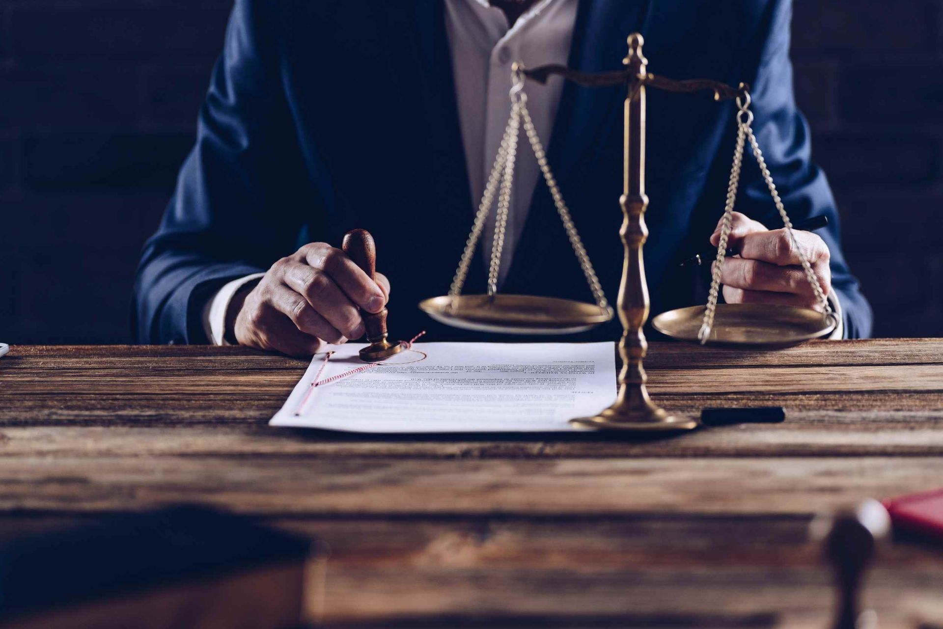 Un hombre con traje está sentado en una mesa con una balanza de justicia.