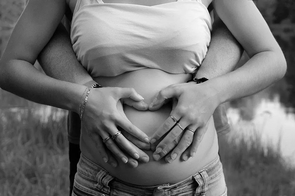 Ventre de femme enceinte avec mains des parents dessus