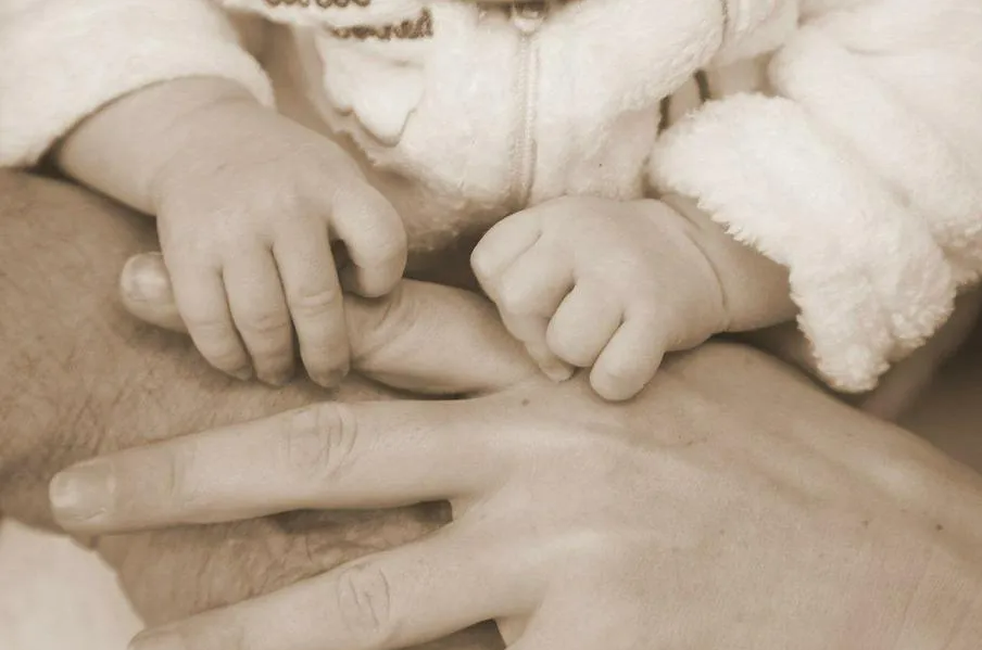 Mains d'un bébé tenant le doigt d'un adulte