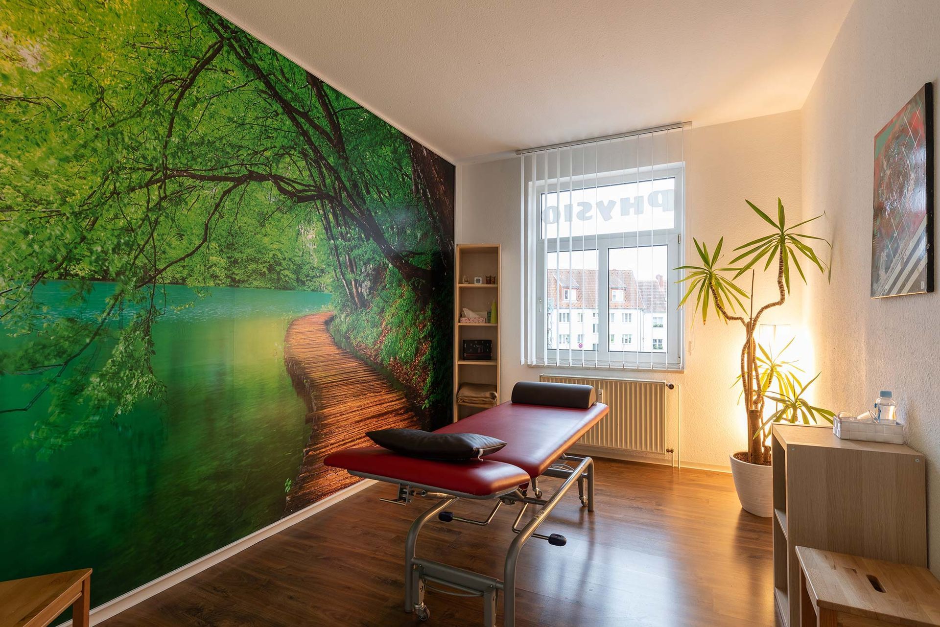 Ein Raum mit einem Massagetisch und einem Baum an der Wand.