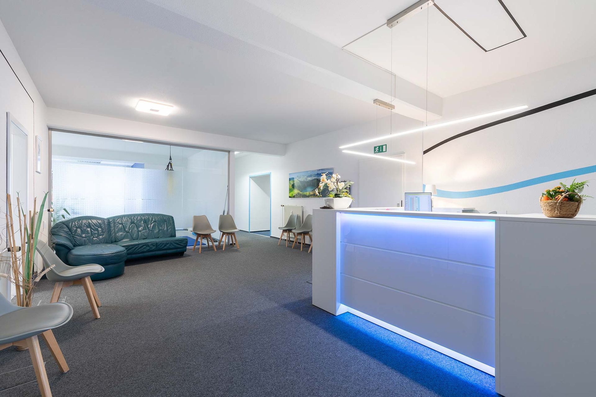 Ein Wartezimmer mit Couch und Stühlen sowie einer Rezeption.