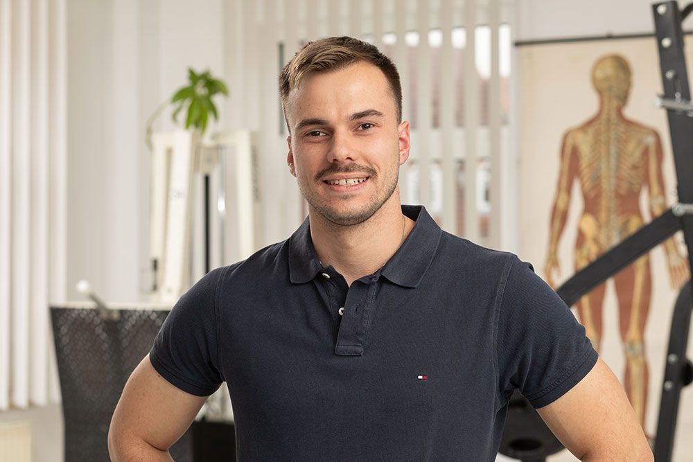 Ein Mann in einem blauen Poloshirt steht mit den Händen in den Hüften in einem Raum.