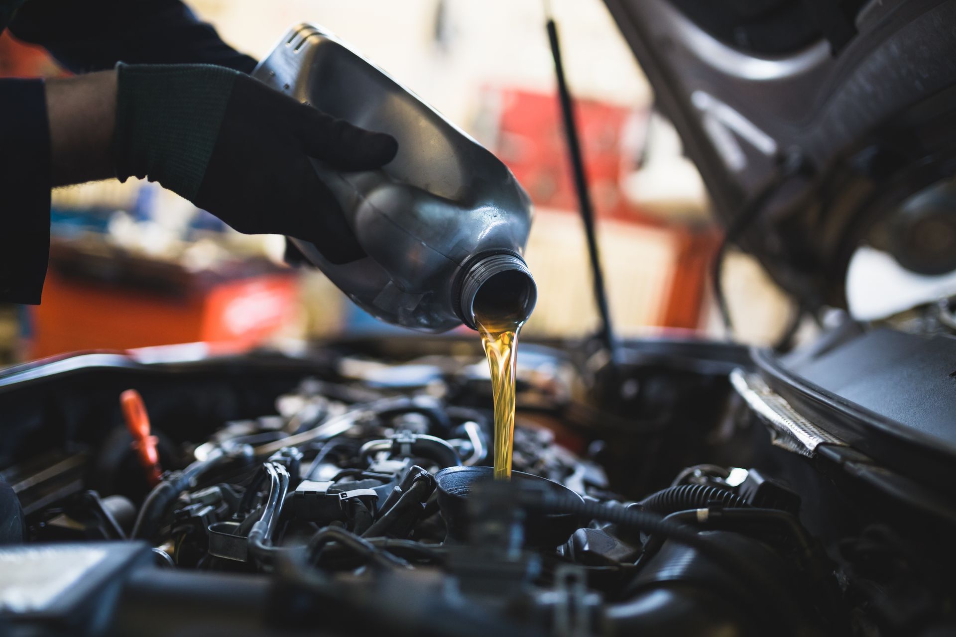 Un mécanicien verse de l'huile dans un moteur de voiture.