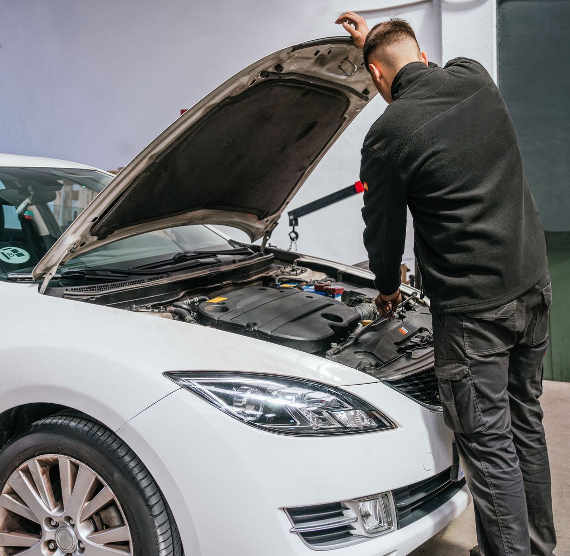 Un mécanicien soulève le capot d'une voiture.