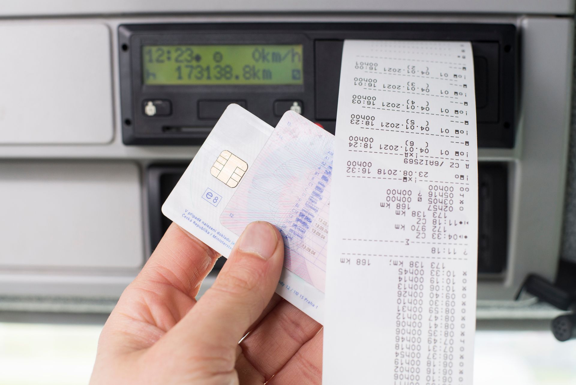 Gros plan sur un conducteur tenant sa carte de conducteur et son tachygraphe numérique.