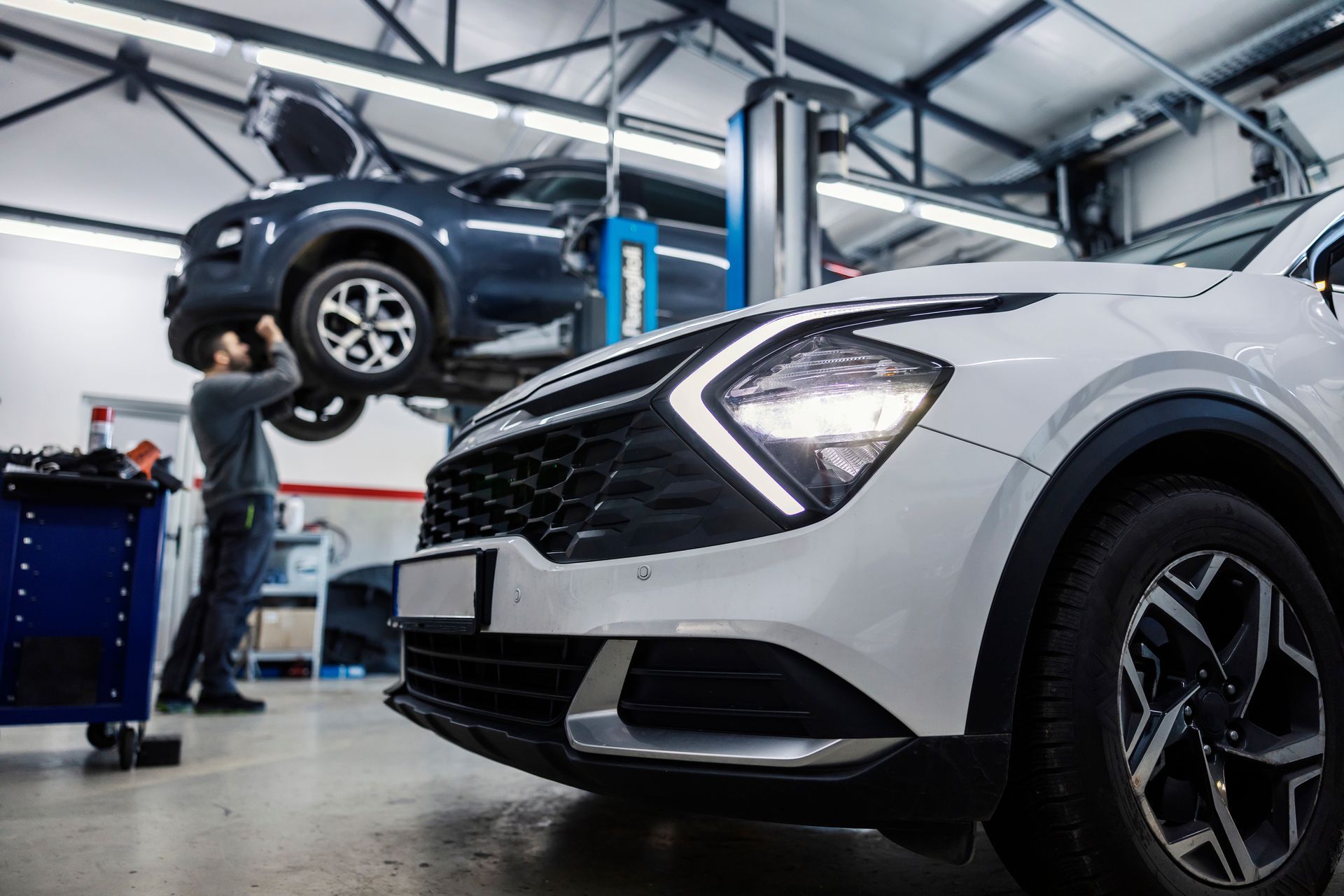 L'intérieur d'un garage automobile avec plusieurs voitures et un mécanicien.