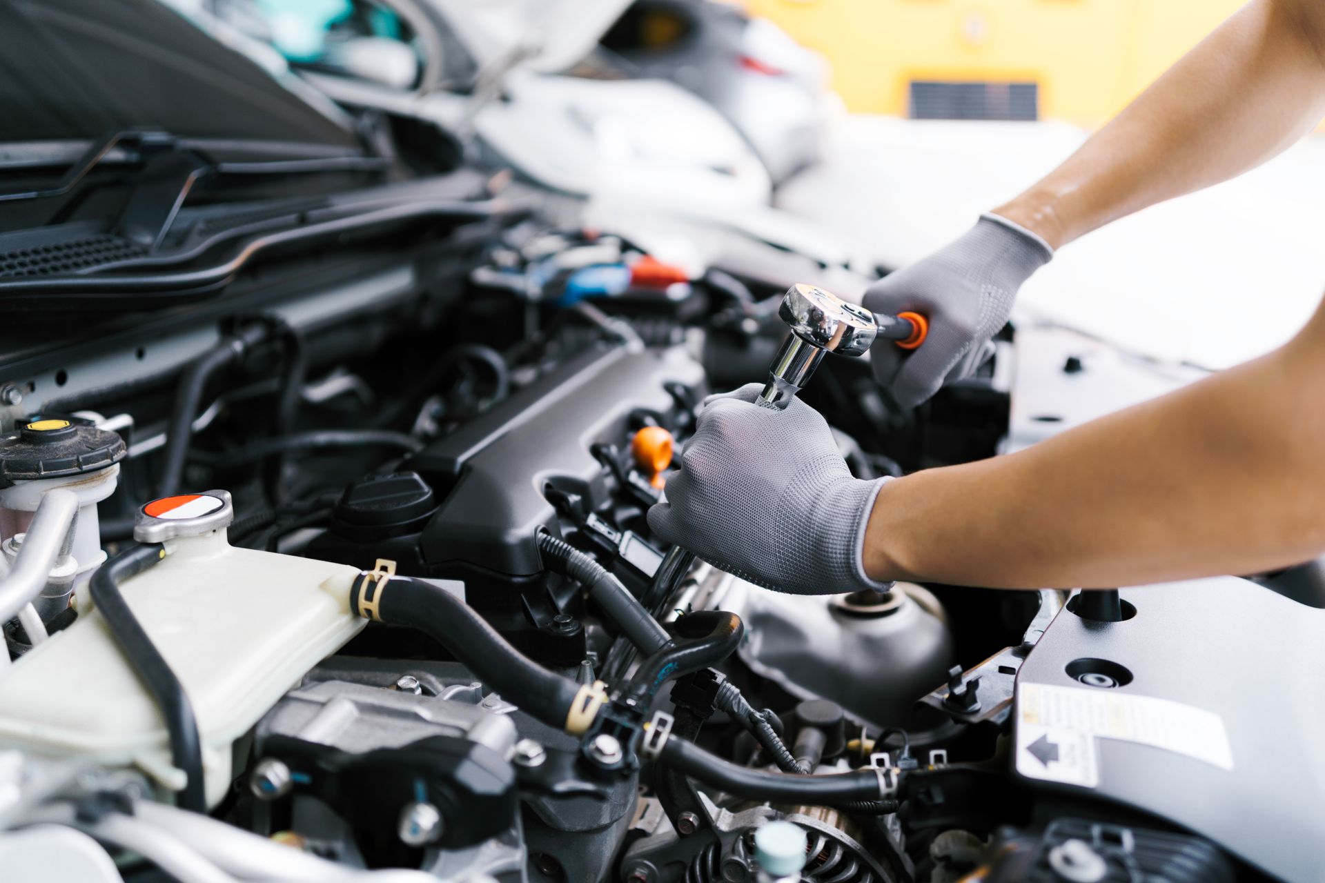 Intervention sur un moteur de voiture, mains gantées.