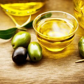 Hay un recipiente con aceite de oliva y aceitunas en la mesa.