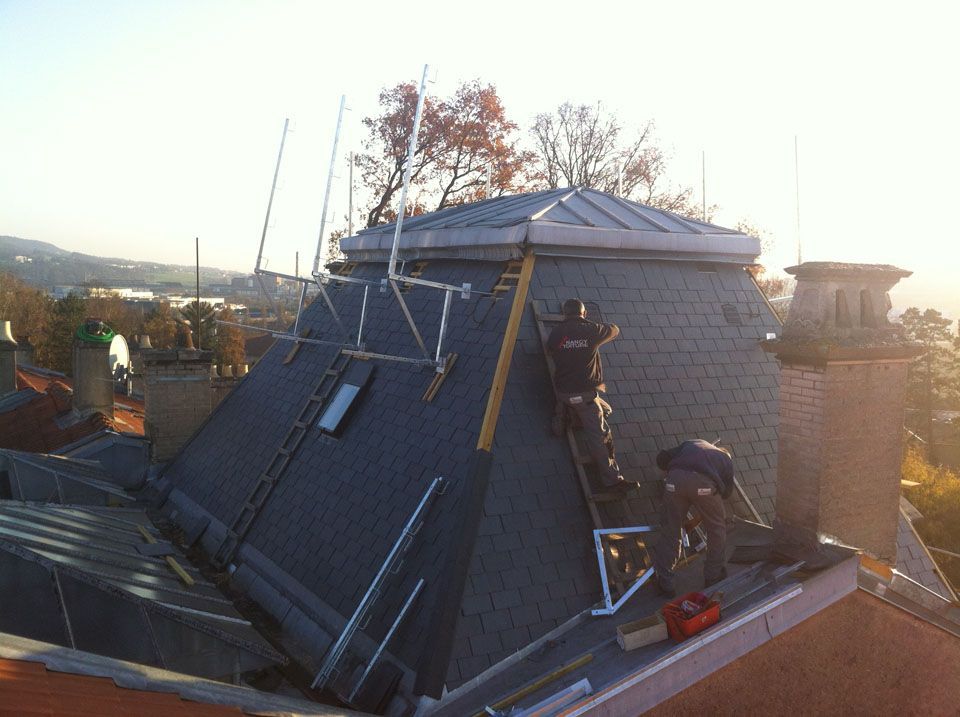 Des ouvriers qui font les finitions d'une toiture en ardoise