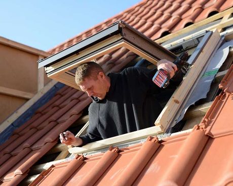 Ouvrier qui installe une fenêtre de toit depuis l'intérieur