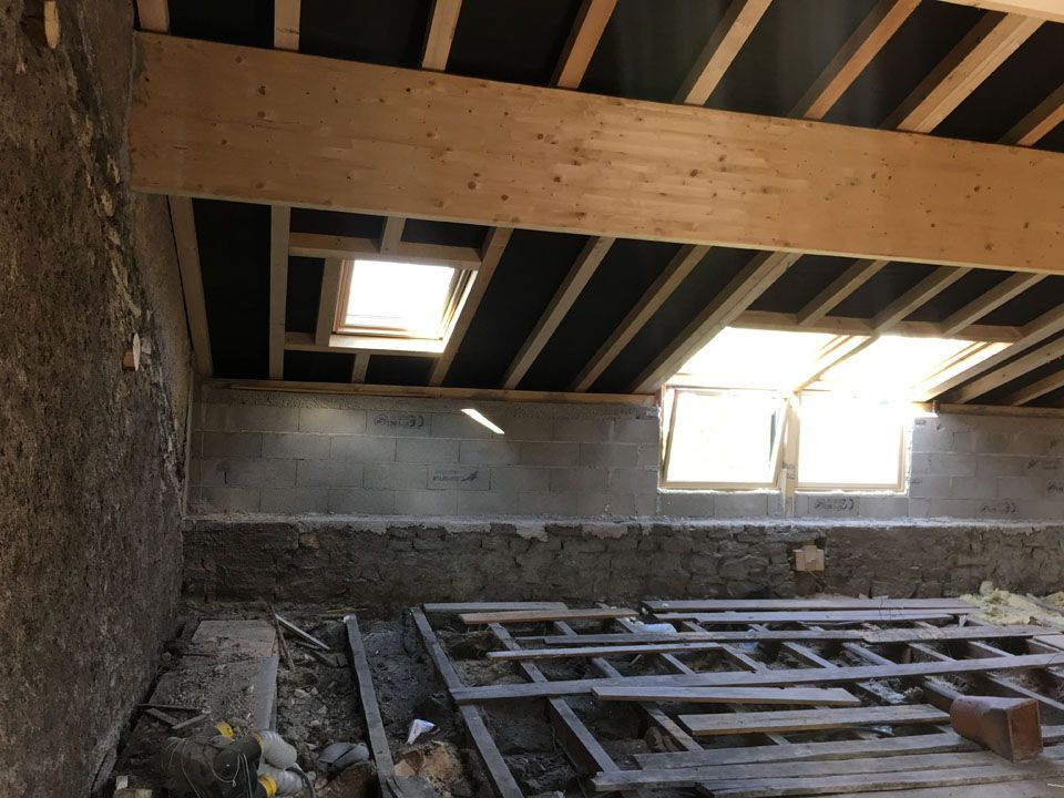 Vue depuis les combles d'une charpente avec une fenêtre de toit