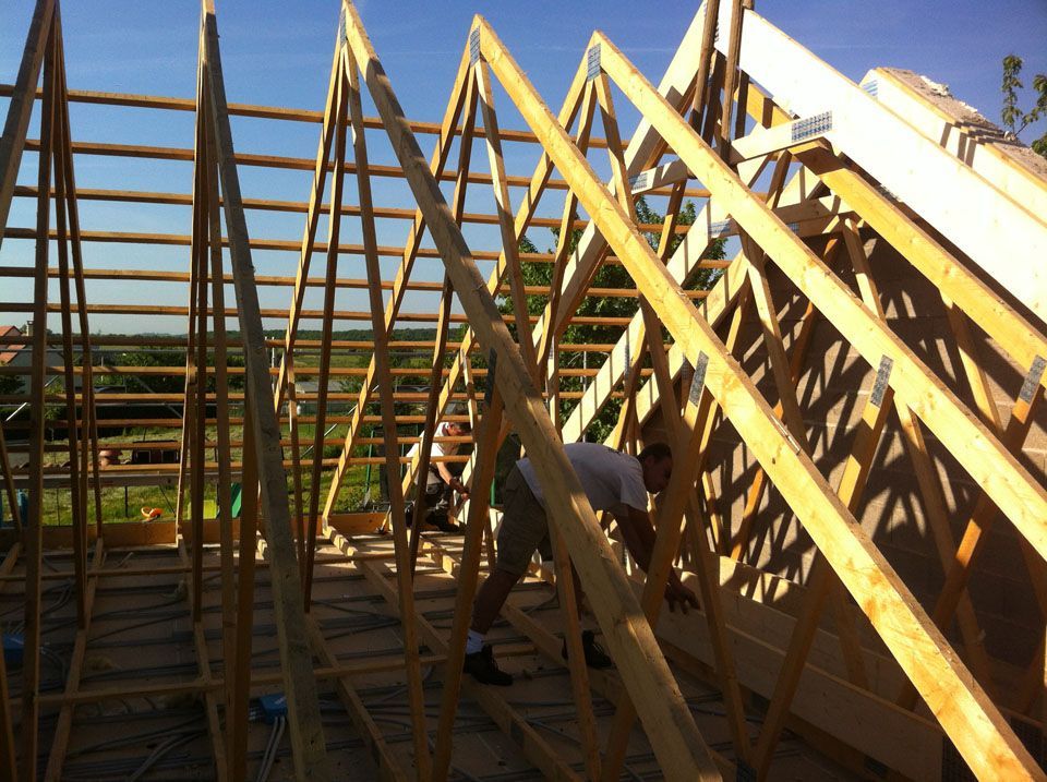 Deux ouvriers en train de travailler sur une charpente en bois