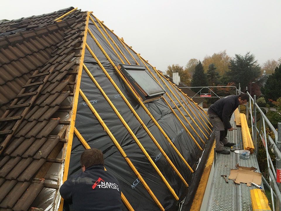 Deux ouvriers qui couvrent une toiture avec un Velux