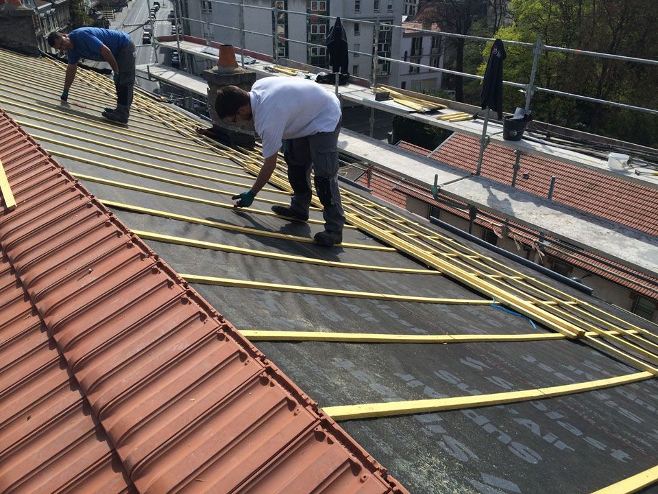 Des ouvriers qui sont en train de procéder au litonnage de la toiture