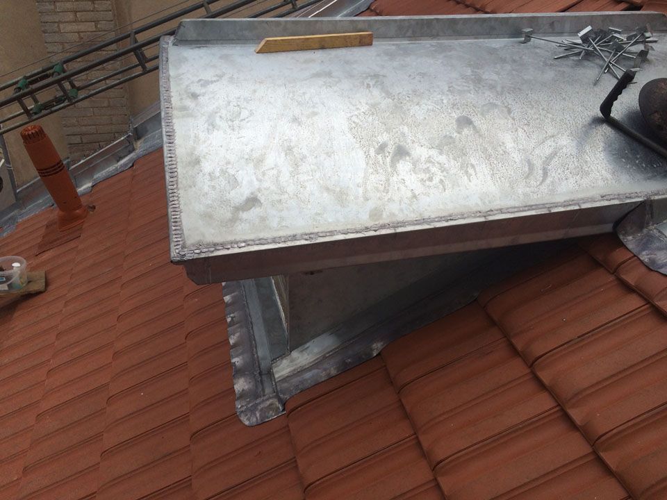 Chien assis en zinc sur une toiture en tuiles