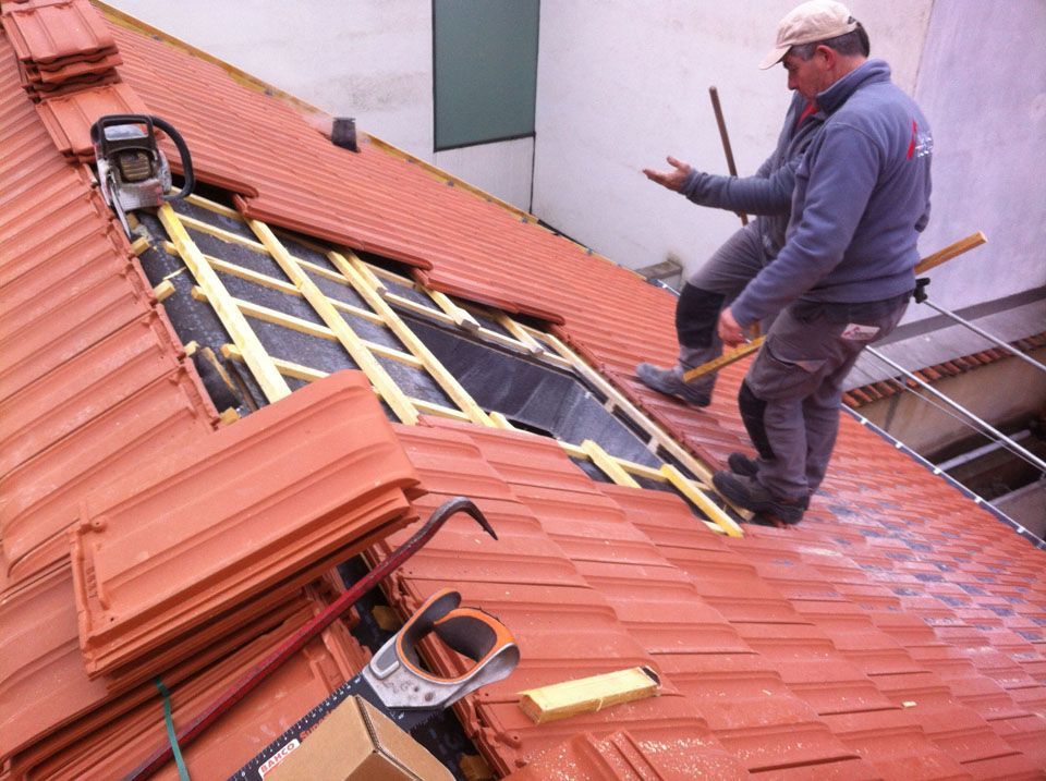Deux ouvriers sur le toit en train de préparer la couverture pour l'installation d'un velux