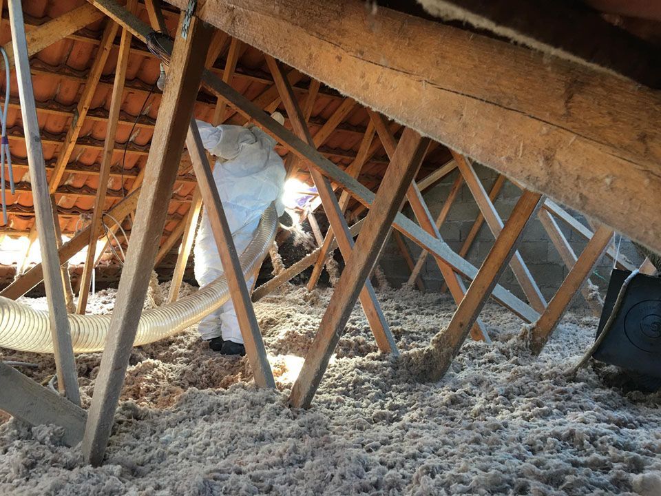 Un ouvrier en combinaison qui souffle de la mousse isolante