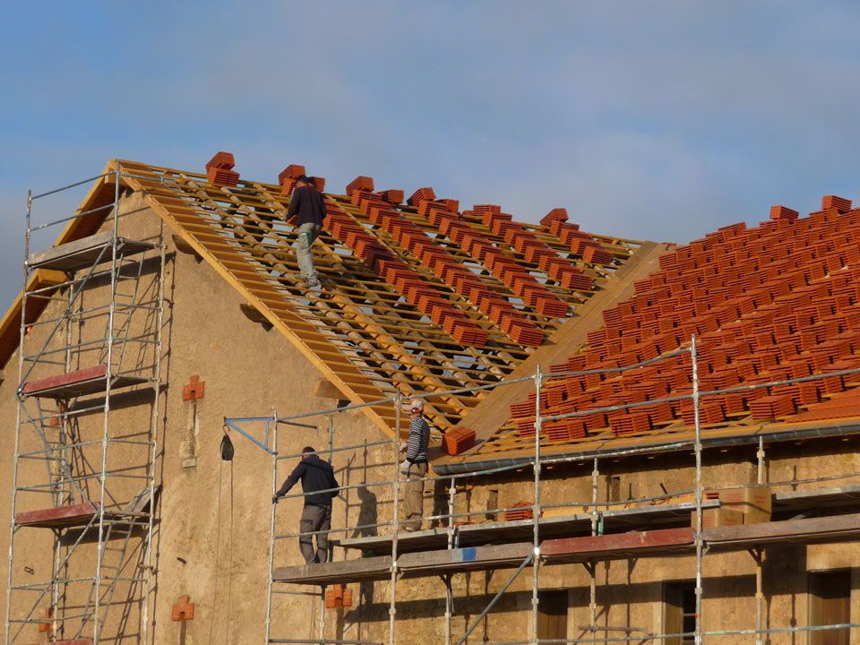 Ouvriers sur un toit en train de poser des tuiles