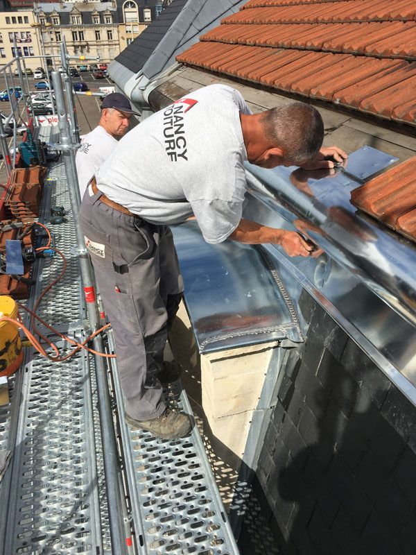 Installation de zinguerie sous une toiture en tuiles