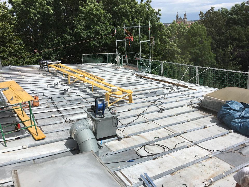 Travaux d'installation d'un grand bardage en zinc sur un toit