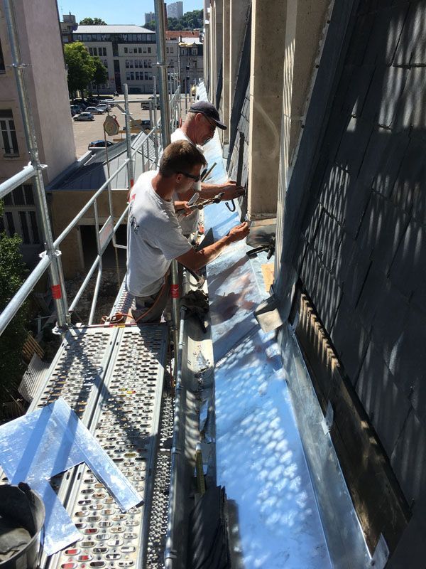 Installation de zinguerie sous une toiture en ardoise