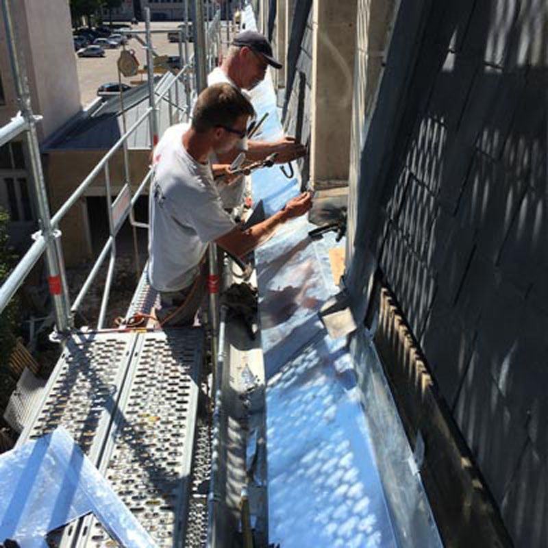 Installation de zinguerie sous une toiture en ardoise
