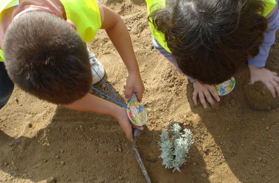 Un niño y una niña están mirando algo en la tierra.