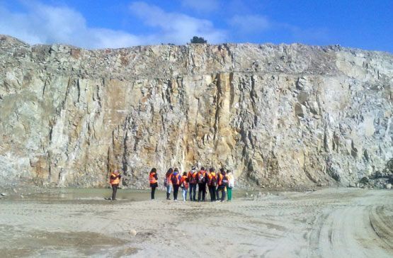 Un grupo de personas está de pie frente a una gran pared de roca.