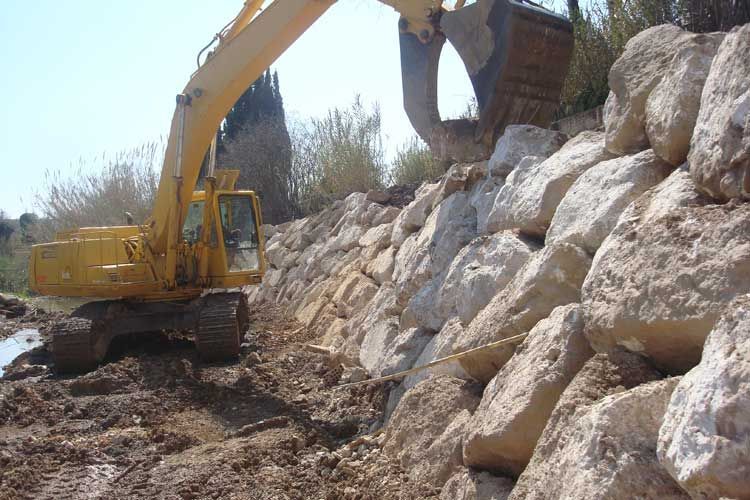 Una excavadora amarilla está trabajando en una pila de rocas.