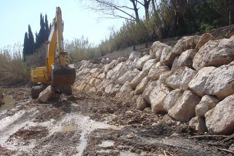 Una excavadora amarilla está trabajando en una pared de roca.