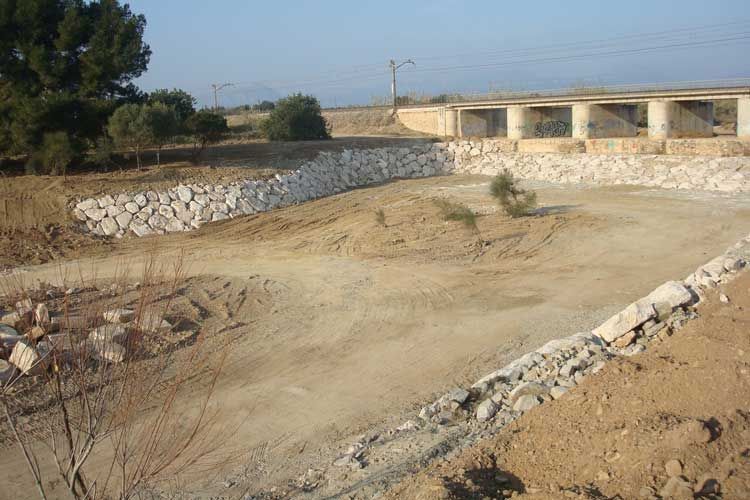 Un camino de tierra con un muro de piedra al fondo
