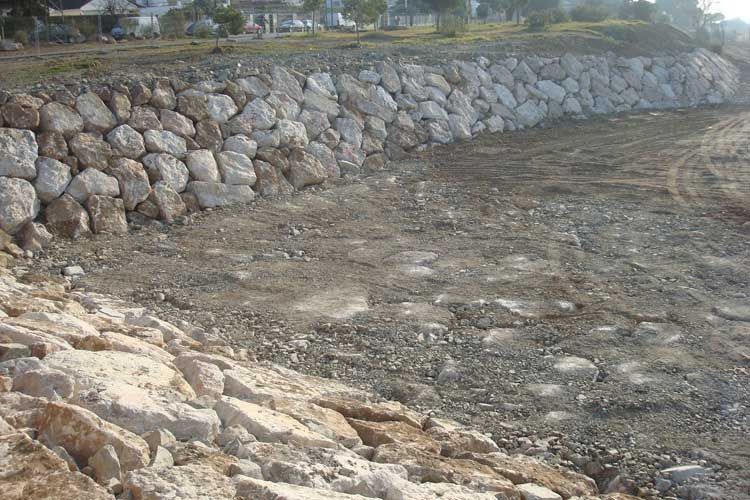 Se está construyendo un gran muro de roca al costado de un río.