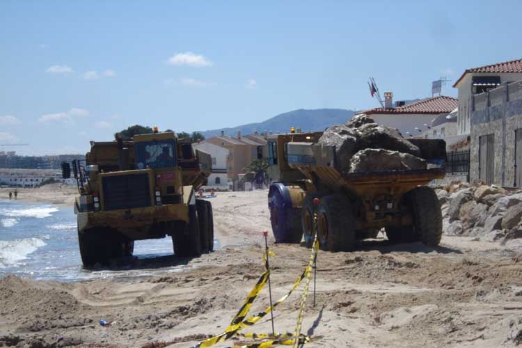 Dos camiones están estacionados en una playa de arena cerca del océano.