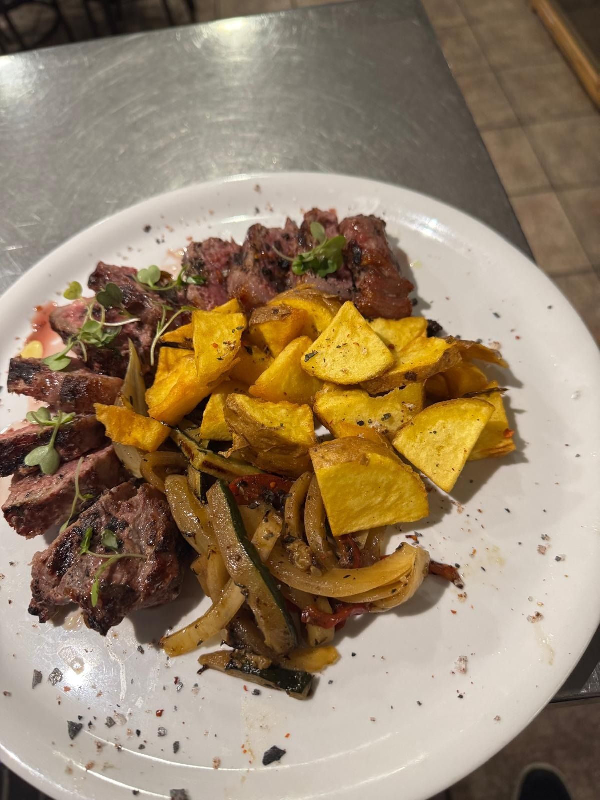 Filete emplatado con cebollas salteadas y totopos tostados en un plato blanco.