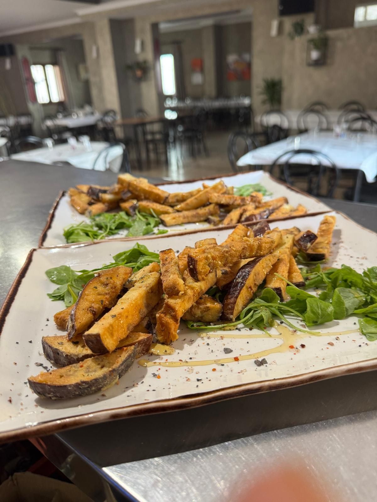 Plato de aperitivos fritos sazonados en una bandeja blanca en el comedor de un restaurante.