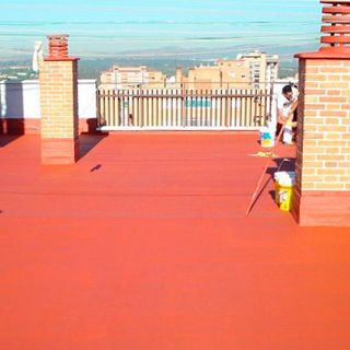 Un hombre está pintando un techo rojo con una escoba.
