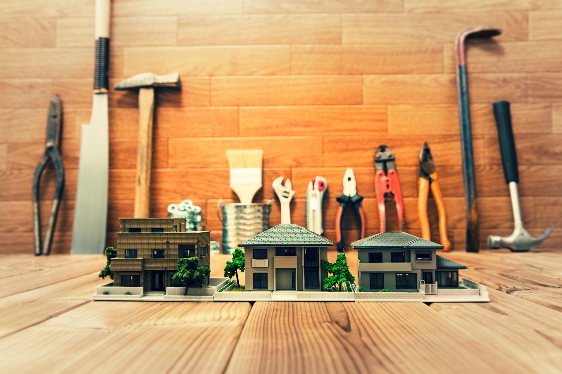 Ein Holztisch mit einem Modellhaus und Werkzeugen darauf