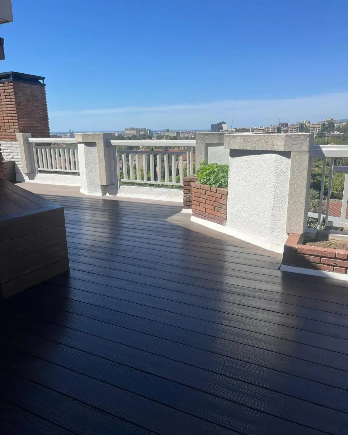 Terraza en la azotea con pisos de apariencia de madera oscura, detalles de ladrillo y hormigón,