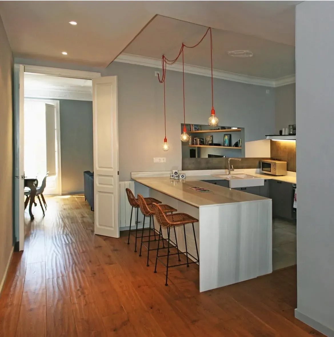 Escalera de madera con pasamanos metálico. Obras de arte y un reloj decoran las paredes.