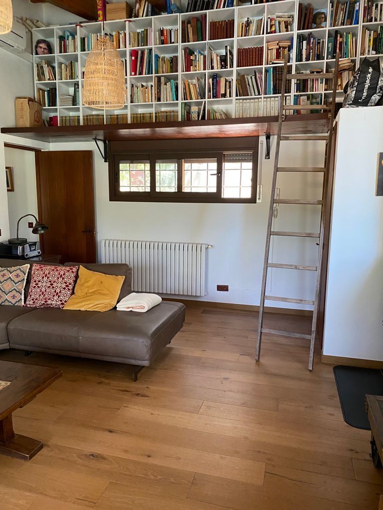 Cocina espaciosa y luminosa con pisos de madera, gabinetes blancos y una mesa de comedor de madera.
