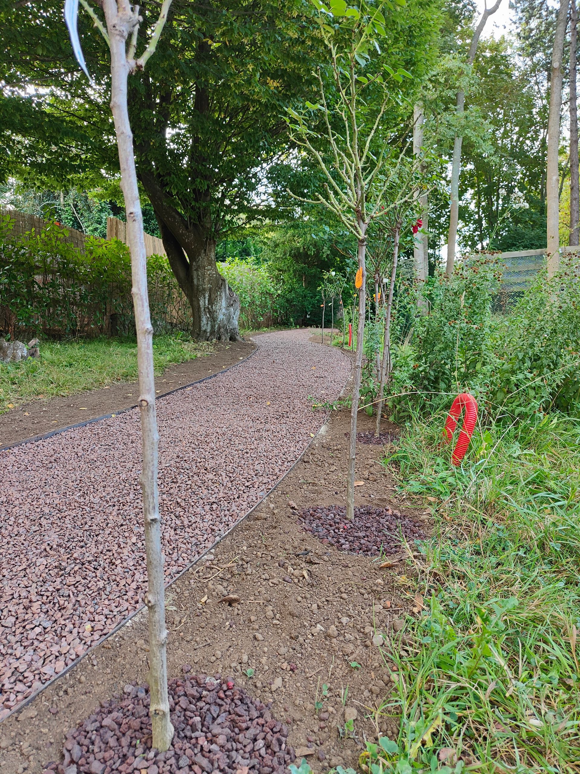 Une allée de jardin avec des graviers rouges