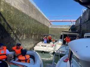 Passage d’une écluse lors d’une formation pratique au permis bateau, avec plusieurs embarcations et leurs occupants équipés de gilets de sauvetage.