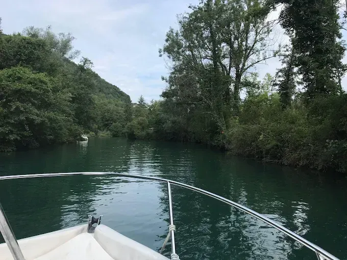 Navigation en bateau à moteur sur une rivière bordée d’arbres, dans un environnement calme propice à l’apprentissage des manœuvres et de la conduite.